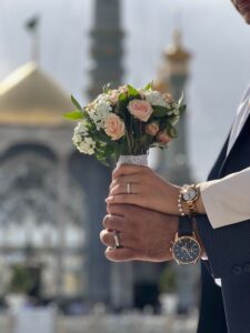 عکس دست‌های عروس و داماد با دسته گل رز هلویی و ساعت مچی