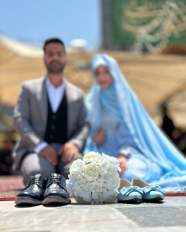 عکس کفش و دسته گل رز سفید با زوج و چادر آبی در پس‌زمینه
