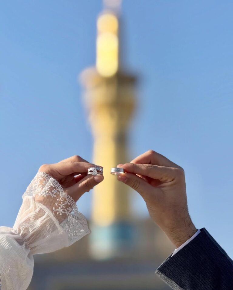 عکس دو حلقه ازدواج مقابل گلدسته طلایی و آسمان آبی