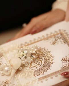 عکس حلقه ازدواج روی جلد تذهیب‌کاری‌شده قرآن با مروارید