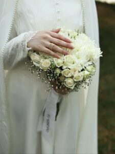 عکس عروس با مانتو کرم مروارید دوزی و دسته گل رز سفید