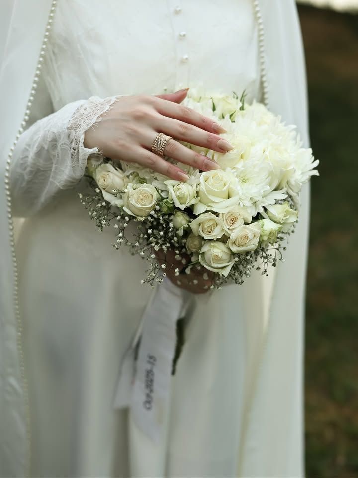 عکس عروس با مانتو کرم مروارید دوزی و دسته گل رز سفید